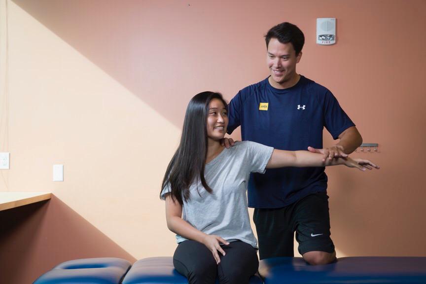 Physical therapist testing shoulder abduction strength