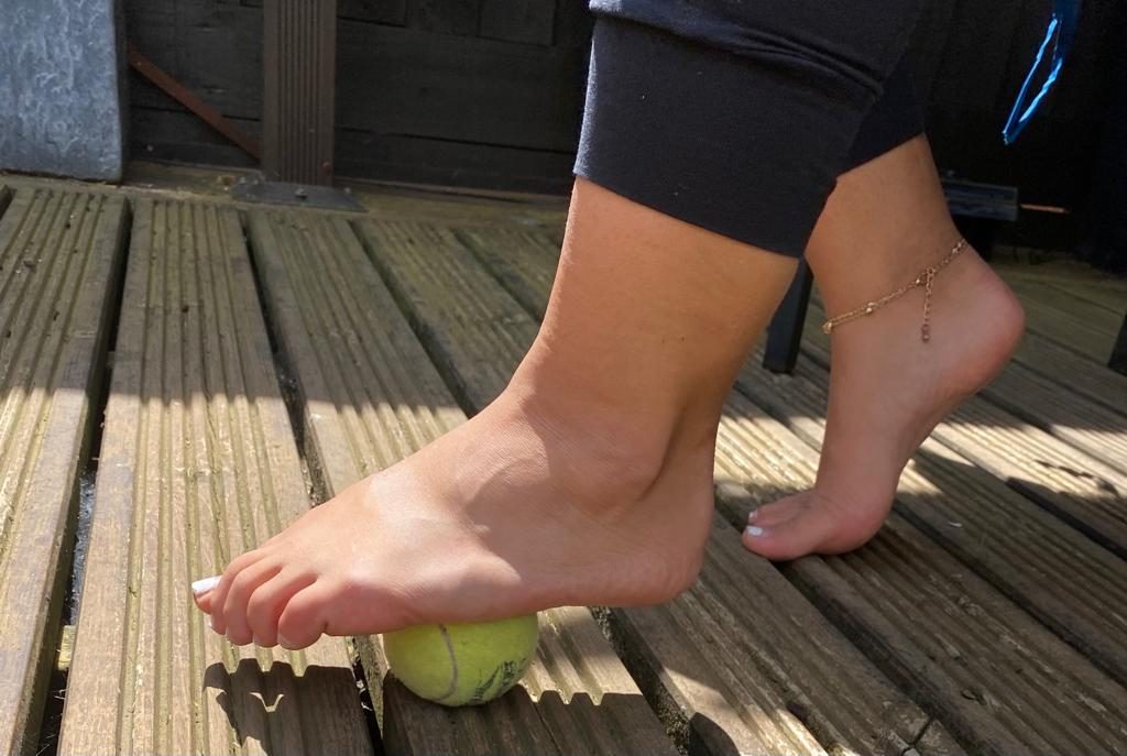 Massaging foot with a tennis ball