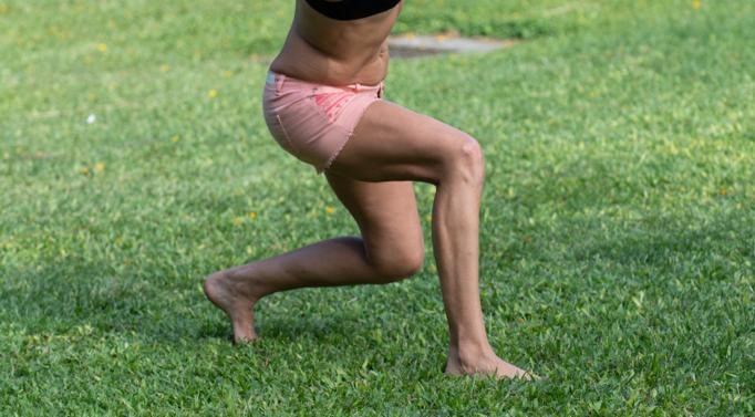Woman is lunging while on grass
