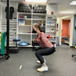 Woman squatting in physical therapy clinic setting