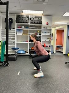 Woman squatting in physical therapy clinic setting