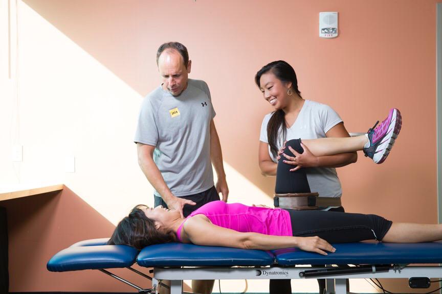 Physical therapists treating a woman's hip with a traction belt
